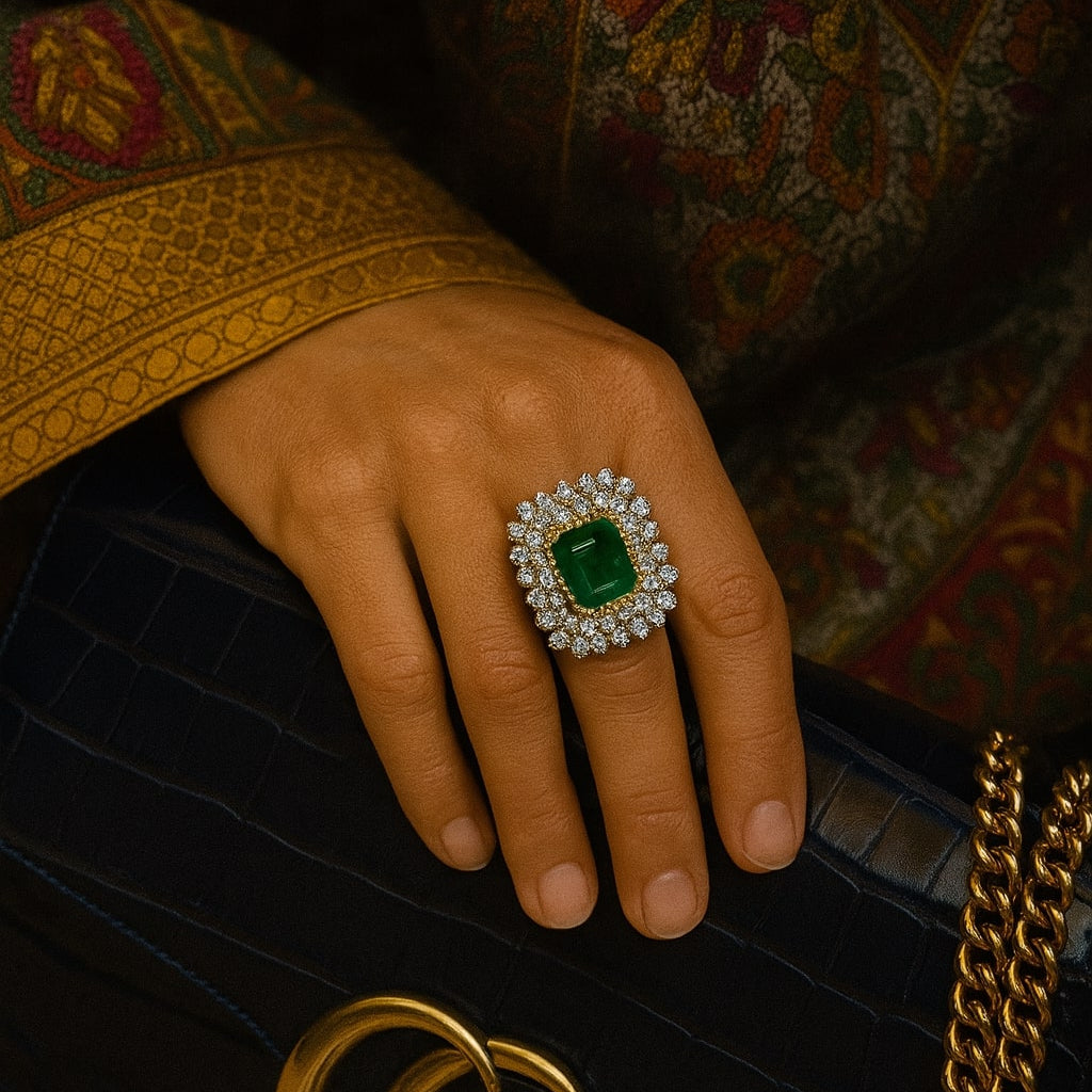 Hand wearing a diamond and emerald ring with a Gucci handbag in the background